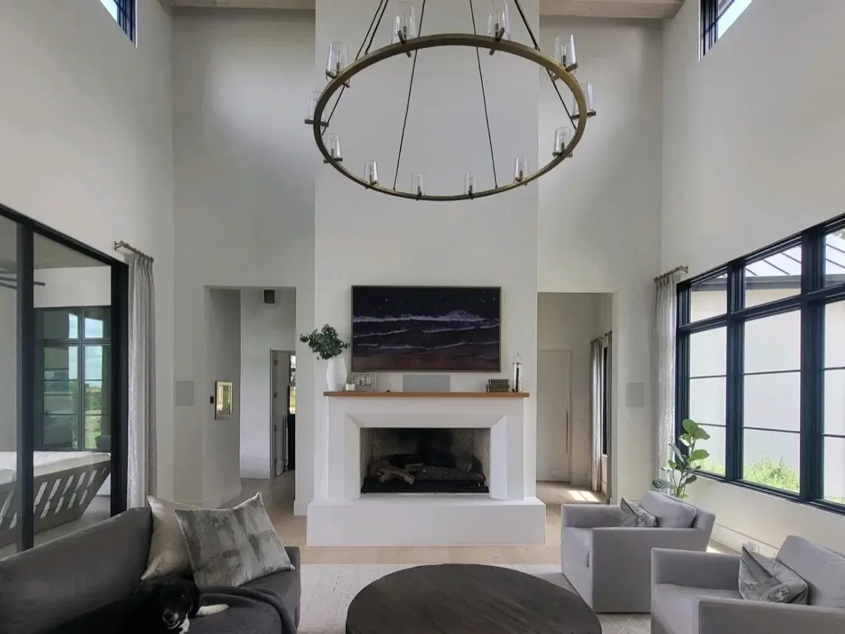 Two-story living room with a TV above the fireplace under a ring chandelier. Home audio and video installation in Bee Cave, TX by AV Connect.