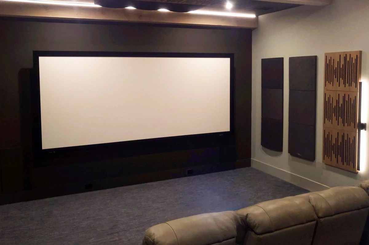 A dedicated home theater with a large fixed projection screen, acoustic wall treatments, and leather seating in an Austin, TX home