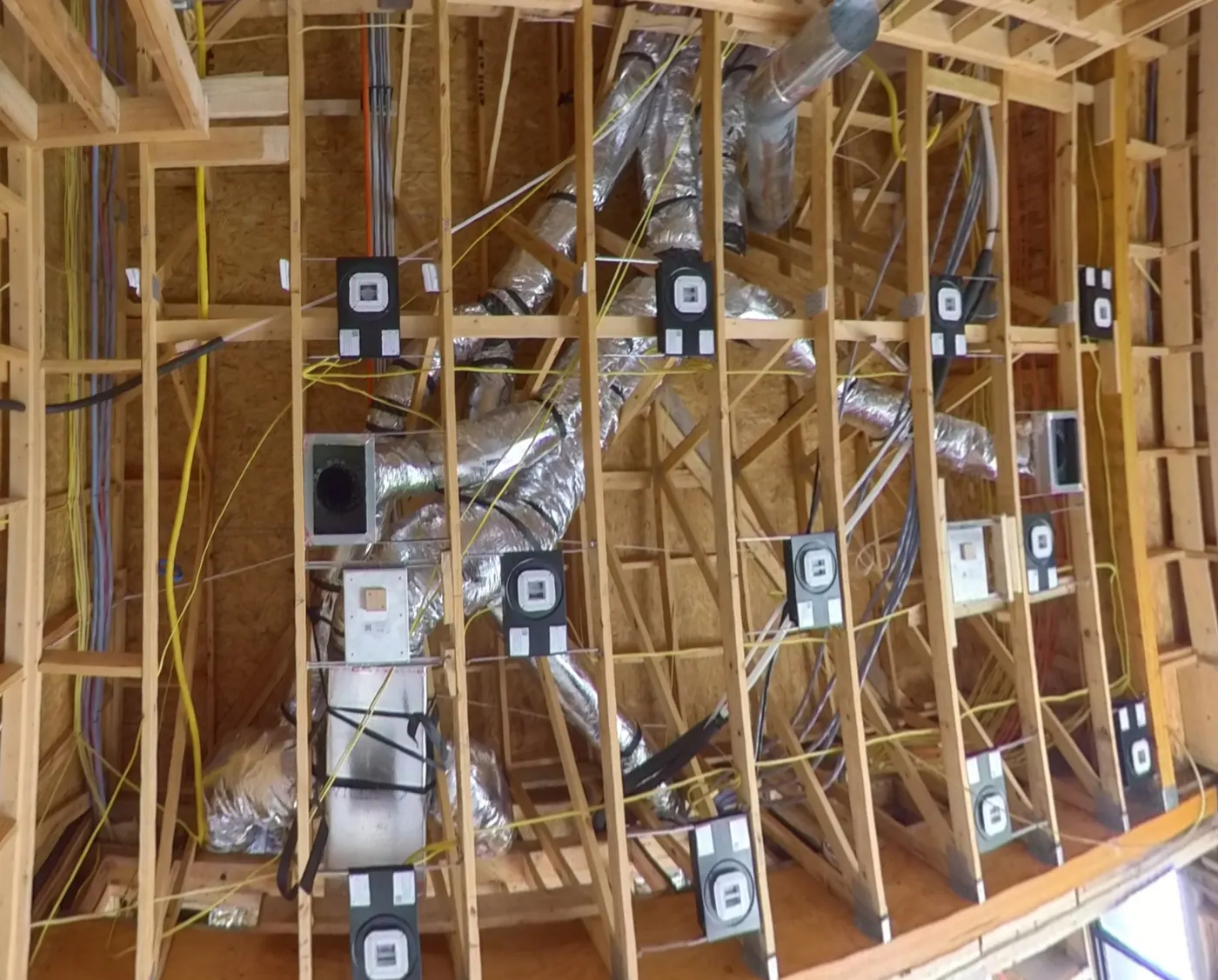 Speaker and network wiring run through open ceiling framing alongside HVAC ductwork during new construction, by AV Connect in Austin, TX