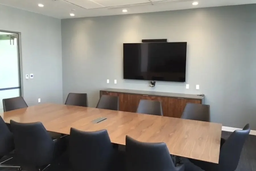 Conference room with a wall-mounted display and video camera above a credenza. Staff training and support for Bee Cave, TX businesses by AV Connect.