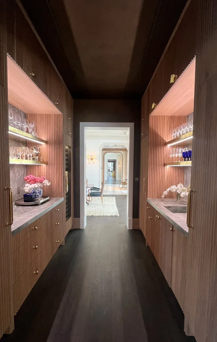 Narrow bar passage with lit glass shelving on both sides, an example of the lighting and motorized shade installation AV Connect provides for Lakeway, TX homes.