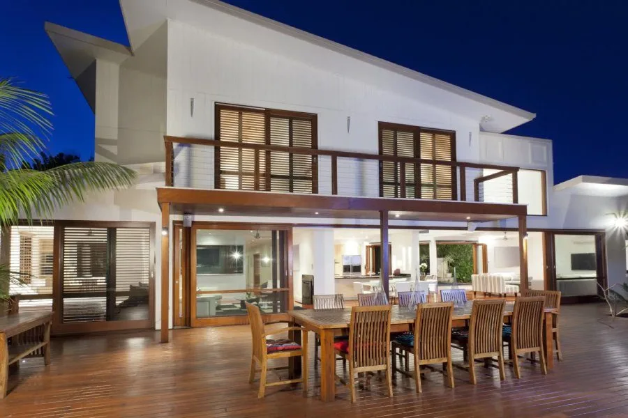 Two-story home with a long dining table on the deck, lit at dusk. Outdoor system walkthrough for Bee Cave, TX homes by AV Connect.
