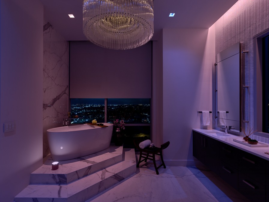 A modern bathroom illuminated by purple and white lighting in a Lutron system. 