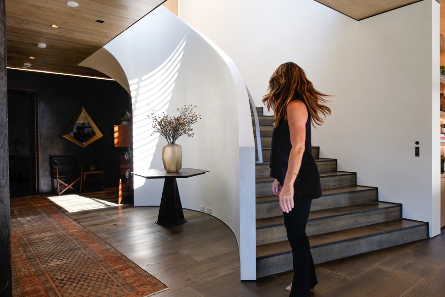 A woman approaches stairs in a modern Austin home with voice-controlled smart features, showcasing sleek architecture and natural light.