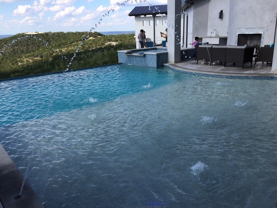 An Austin pool and patio with an outdoor kitchen, fireplace, and audio system.