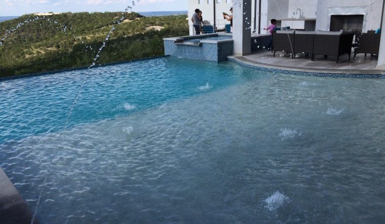 an austin pool and patio with an outdoor kitchen, fireplace, and audio system.