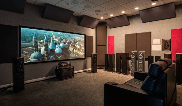 client’s showroom home theater setup with several floorstanding speakers, a single chair, and a screen featuring blue towers.