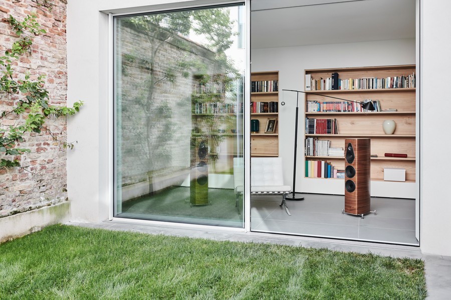 a modern home in austin with large glass doors revealing a wooden bookshelf and a pair of high end audio speakers.